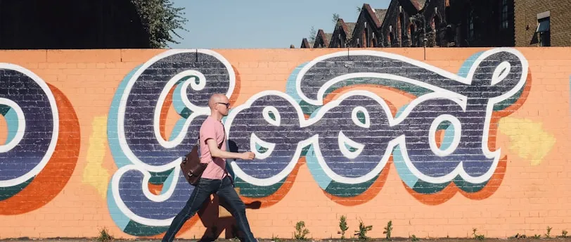 man walking beside graffiti wall